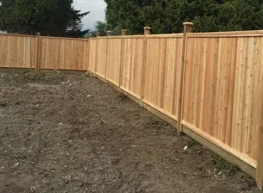 Cedar fence with post caps on freshly graded ground